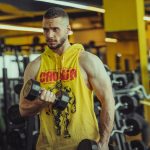 a man in a gym holding a pair of dumbs