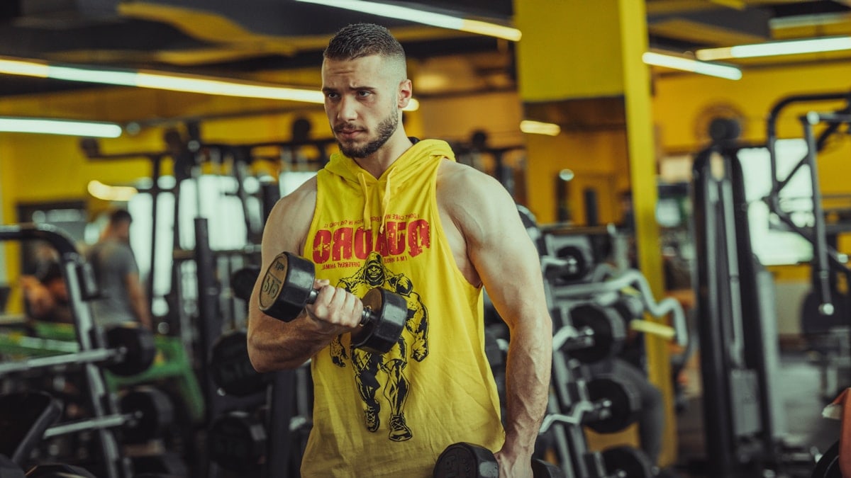 a man in a gym holding a pair of dumbs